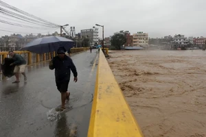 Người dân đi qua cầu bắc qua sông Bagmati tại Kathmandu. Phía kế bên có thể thấy mực nước đang dâng rất cao. (Ảnh: Reuters)