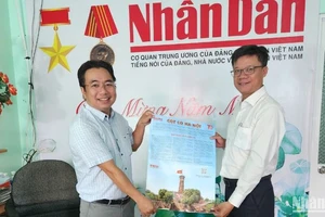 Thầy Phan Quốc Nam (bên phải), Hiệu trưởng Trường trung học cơ sở Võ Nguyên Giáp trực tiếp nhận phụ san Báo Nhân Dân về Cột cờ Hà Nội. 