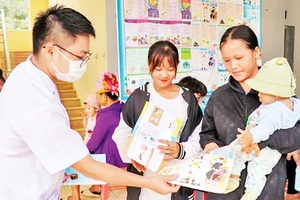 Cán bộ Trạm Y tế xã Mường Cai, huyện Sông Mã, tỉnh Sơn La phát tờ rơi tuyên truyền về công tác dân số cho nhân dân. (Ảnh HUYỀN TRANG)