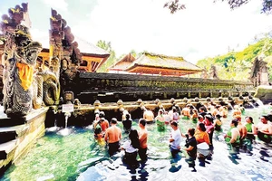 Người dân và du khách xếp hàng chờ đến lượt thực hiện nghi thức tắm nước suối thiêng ở đền Tirta Empul.