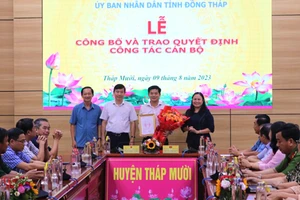 Ông Phạm Thiện Nghĩa trao quyết định, Bí thư Huyện ủy Tháp Mười Trần Thị Quý tặng hoa chúc mừng ông Đoàn Thanh Bình. (Ảnh: THÀNH NHƠN)