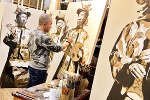 Họa sĩ Võ Thành Thân trong xưởng vẽ với bộ tranh lấy cảm hứng từ văn hóa truyền thống Huế. (Ảnh: NVCC)