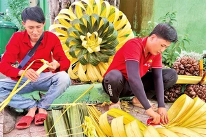 Nhóm bạn trẻ tại Tổ hợp tác cổng rạp cưới "Alo Tui" tạo hình trang trí cưới từ lá dừa.