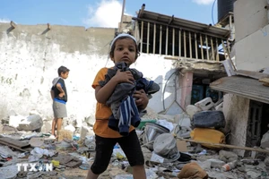 Các em nhỏ thu nhặt đồ đạc sót lại trong đống đổ nát của ngôi nhà bị phá hủy sau cuộc tấn công của Israel vào thành phố Rafah, Dải Gaza ngày 1/5/2024. (Ảnh: THX/TTXVN)