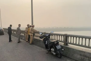 Chiến sĩ Cảnh sát giao thông Công an tỉnh Hưng Yên đang cùng người dân động viên người phụ nữ từ bỏ ý định tự tử trên cầu Yên Lệnh.