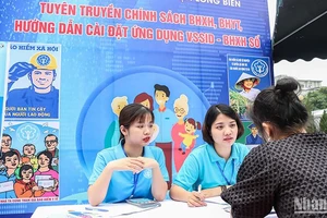 Cán bộ Bảo hiểm xã hội quận Long Biên, Hà Nội giới thiệu chính sách với người lao động. (Ảnh: NGÂN ANH)