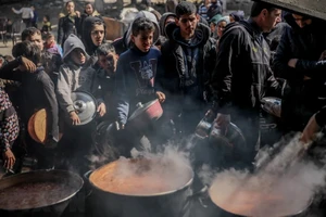 Người dân Palestine nhận thức ăn cứu trợ tại Beit Lahia, phía Bắc Dải Gaza ngày 26/2/2024. (Ảnh: AFP/TTXVN)