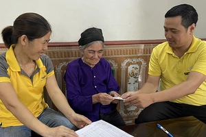 Bà Chu Thị Hỵ, xã Sàn Viên, huyện Lộc Bình, tỉnh Lạng Sơn, được nhân viên bưu điện chi trả tiền trợ cấp tuất tại nhà. (Ảnh: Vietnam Post)
