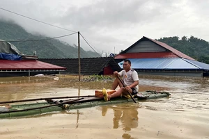 Một hộ dân ở xã Nam Cường, huyện Chợ Đồn di chuyển qua nước ngập bằng bè tre đi nhận nhu yếu phẩm hỗ trợ. (Ảnh: ĐÌNH HỢI).