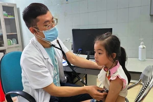 Cán bộ y tế khám, kiểm tra sức khỏe ban đầu cho trẻ em.