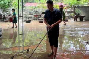 Hộ gia đình chủ động gạt bùn, làm vệ sinh nhà ở sau ngập nước.