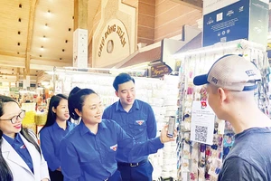 Đoàn viên, thanh niên quận Hoàn Kiếm hướng dẫn các hộ kinh doanh, người mua hàng tại chợ Đồng Xuân sử dụng mã QR khi thanh toán.