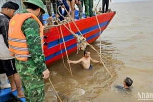 Huy động thợ lặn xuống nước buộc dây để lai dắt tàu cá bị chìm vào bờ.