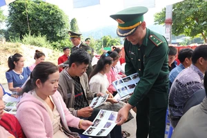 Cán bộ, chiến sĩ Bộ đội Biên phòng tỉnh Điện Biên phát tờ rơi tuyên truyền bảo vệ rừng đến nhân dân trên khu vực biên giới Việt-Lào.