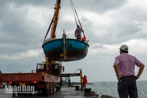 Ngư dân tại khu vực vịnh Sơn Trà dùng xe cẩu đưa thuyền máy lên bờ tránh bão. (Ảnh: Công Vinh) 