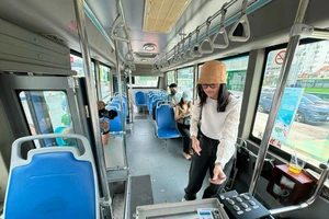 Hành khách "chạm" để thanh toán khi đi xe buýt bằng hệ thống thanh toán tự động.