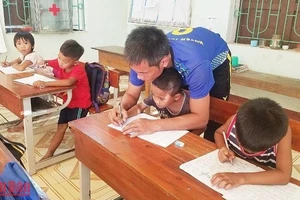 Thầy giáo dạy học sinh đồng bào Mã Liềng ở huyện Tuyên Hóa (Quảng Bình) viết chữ.