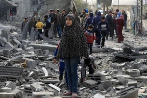 Người dân Palestine bên đống đổ nát của những tòa nhà bị phá hủy sau các cuộc không kích của Israel tại thành phố Rafah, Dải Gaza. (Ảnh: THX/TTXVN)