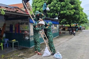 Cán bộ, chiến sĩ Đồn Biên phòng Cửa khẩu cảng Vạn Gia giúp nhân dân chằng chống, gia cố nhà cửa trước khi bão đổ bộ.