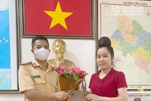 Thượng úy Lê Lâm Tùng trả lại chiếc túi xách cho chị Lường Thị Giang.