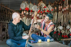 Du khách người Ý thích thú tìm hiểu các nhạc cụ truyền thống Gia Rai dưới sự hướng dẫn của Nghệ nhân Ưu tú Rơ Châm Tih. Ảnh: Nguyễn Linh Vinh Quốc