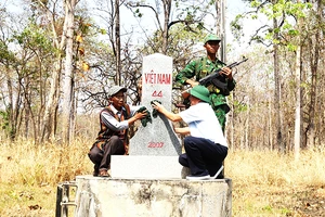 Già làng, người có uy tín xã biên giới Krông Na, huyện Buôn Ðôn (Ðắk Lắk) lau chùi cột mốc chủ quyền biên giới quốc gia trên địa bàn. 