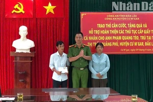 Thượng tá Lê Văn Khánh, Phó Trưởng Công an huyện Cư M'gar trao căn cước công dân và số tiền do cán bộ, chiến sĩ Công an huyện quyên góp tặng cho vợ chồng anh Phạm Quang Tèo.