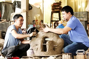 Anh Nguyễn Văn Huỳnh (bên phải) cùng thợ hoàn thiện khuôn đúc đồng.