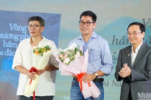 Ông Lương Minh Sâm, Chủ tịch Hội đồng Trường đại học Đông Á tặng hoa chúc mừng hai tác giả Trần Tuấn và Hồ Tấn Vũ. (Ảnh: ANH ĐÀO)