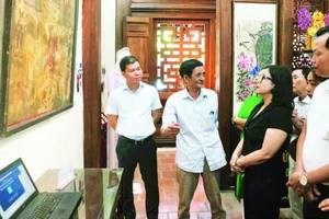 Nghệ nhân Lê Đình Nghiên (thứ hai từ trái sang) giới thiệu về tranh Hàng Trống trong triển lãm Phục hồi tại đình Nam Hương, quận Hoàn Kiếm.