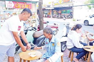 Những khách hàng đến ăn lần đầu, ông Trương Minh Đương (áo trắng) tự tay nấu mì phục vụ khách.