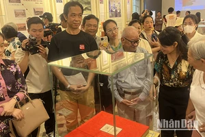 Khách tham quan thưởng lãm block tem kỷ niệm 70 năm Ngày sinh Chủ tịch Hồ Chí Minh có chữ ký của Người. (Ảnh: M.H)