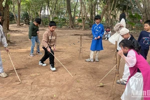 Các em nhỏ thử chơi trò chơi dân gian của người Mường.