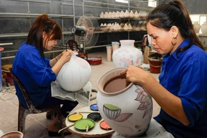 Vẽ hoa văn lên các sản phẩm tại làng gốm Bát Tràng. (Ảnh: ĐĂNG ANH)