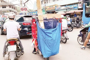 Với bao tải phía sau che kín biển kiểm soát, nhiều shipper vô tư vi phạm luật mà không bị camera giao thông phát hiện. Ảnh: Dũng Phương