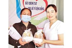 Dược sĩ Lê Thị Thanh Tâm, thành viên “Bếp ăn nhân ái” trao các phần cơm, tặng bệnh nhân đang khám, điều trị tại Trung tâm Y tế huyện Bù Đốp.