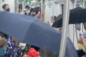 Hành khách phải che ô do nước từ điều hòa tàu chảy xuống sàn chiều 19/5. (Ảnh: cắt từ clip)