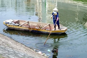Nguồn nước tại các thành phố lớn ngày càng bị ô nhiễm nặng do rác thải, nước thải sinh hoạt xả thẳng ra sông, hồ. (Trong ảnh: Công nhân vệ sinh môi trường nhặt rác nổi trên sông) (Ảnh: DƯƠNG DANH MẠNH)