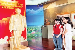Bạn trẻ thưởng lãm tác phẩm “Bác Hồ về thăm quê hương Nghệ An lần thứ hai” của tác giả Nguyễn Xuân Tiên. (Ảnh MẠNH HẢO).