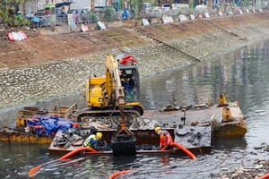 Công nhân Công ty Thoát nước Hà Nội tiến hành nạo vét bùn, cải tạo môi trường nước sông Tô Lịch. (Ảnh: TUẤN SƠN)