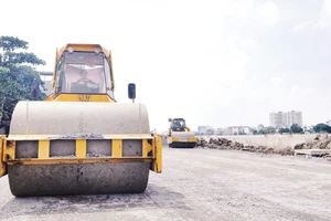 Thi công trải nhựa đường ven kênh Tham Lương, đoạn qua cầu Bến Phân đến cầu An Lộc trên địa bàn Quận 12, Thành phố Hồ Chí Minh. (Ảnh THẾ ANH)