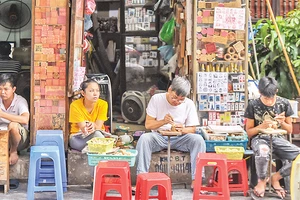 Hình ảnh ông Toàn (thứ hai từ phải sang) miệt mài khắc những con dấu gỗ đã thu hút nhiều khách du lịch khi tới phố cổ Hà Nội. 