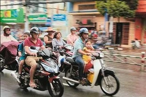 Phụ huynh chở hai cháu không đội mũ bảo hiểm trên đường Quang Trung.