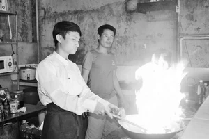 Anh Thắng (bên phải) hướng dẫn cách nấu nướng cho nhân viên.