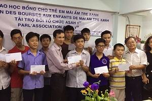 Ông Nguyễn Thanh Tòng (thứ 2, phải sang) trao học bổng cho trẻ em tại Trung tâm Mái ấm Tre xanh ở TP Hồ Chí Minh.