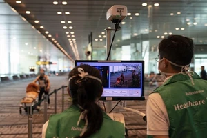 Nhân viên y tế túc trực bên máy đo thân nhiệt hành khách được đặt trong sân bay Changi, Singapore. (Ảnh: Bloomberg)