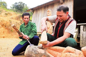 Nghệ nhân Ưu tú A Gông (bên phải) đang truyền dạy lại kỹ năng tạc tượng cho người dân trong làng.