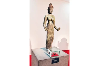 Tượng Bồ tát Tara và hai di vật đóa sen và con ốc trong hộp kính đặt dưới chân tượng. (Ảnh do Bảo tàng Điêu khắc Chăm cung cấp)
