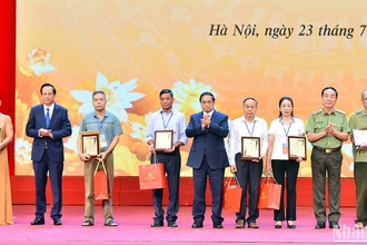 Thủ tướng Phạm Minh Chính và các đại biểu trao kết quả giám định ADN cho đại diện các gia đình liệt sĩ đăng ký giám định ADN. (Ảnh: THỦY NGUYÊN)
