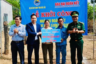 Nhà báo Trương Thành Trung, Tổng Biên tập Báo Đại Đoàn Kết cùng Đại tá Rơ Lan Ngân, Phó Chính ủy, Bộ đội Biên phòng tỉnh Đắk Lắk; lãnh đạo xã Krông Na trao bảng tượng trưng cho gia đình ông Y Hớn Niê. (Ảnh: THANH NGA)